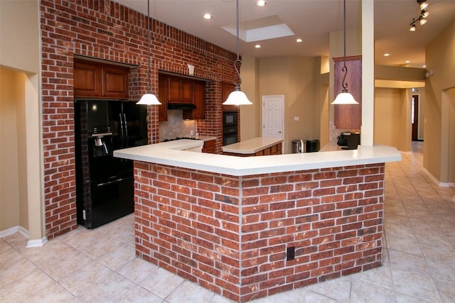 kitchen featuring hanging light fixtures, decorative backsplash, black appliances, and kitchen peninsula