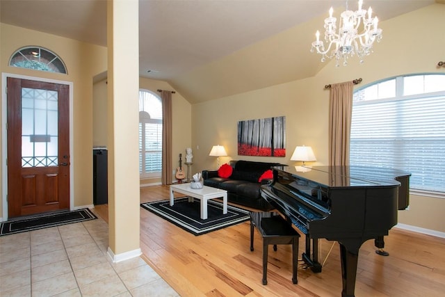 foyer entrance featuring lofted ceiling, light hardwood / wood-style floors, and an inviting chandelier