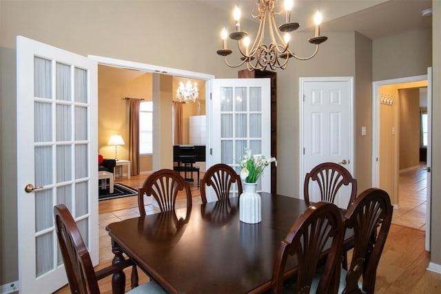 dining area featuring light hardwood / wood-style flooring, french doors, and a chandelier