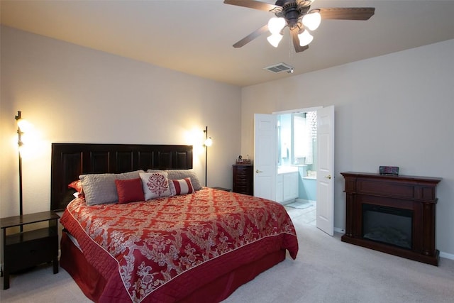 bedroom with ensuite bathroom, light carpet, and ceiling fan