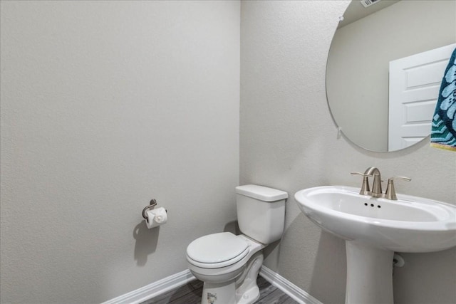 bathroom with wood-type flooring, toilet, and sink