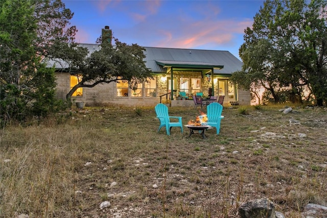 1001 Springlake Dr, Dripping Springs, TX 78620 - back of house featuring metal roof, a chimney, and an outdoor fire pit