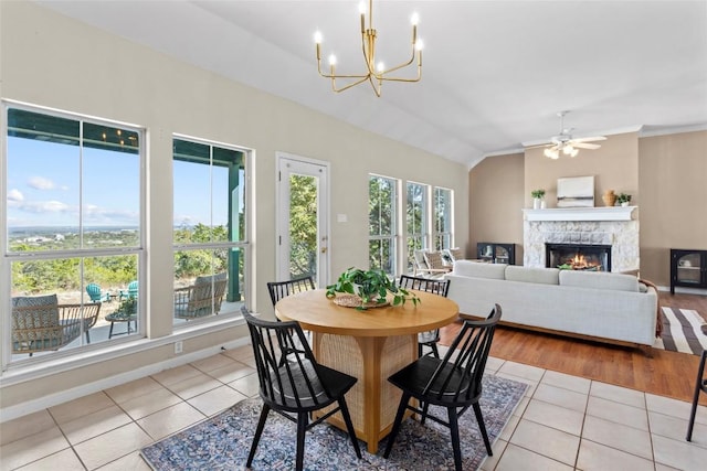 1001 Springlake Dr, Dripping Springs, TX 78620 - dining space featuring light tile patterned floors, a stone fireplace, a chandelier, a ceiling fan, and baseboards