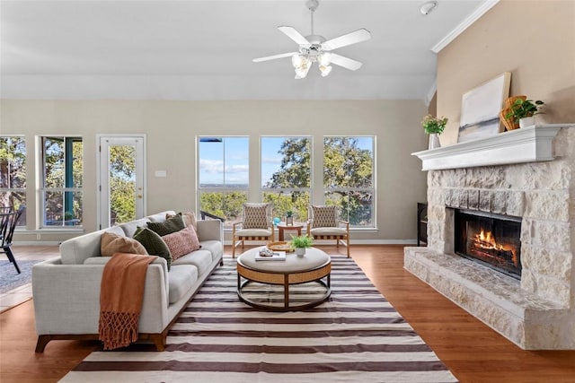 living room with ceiling fan, wood-type flooring, a fireplace, and ornamental molding