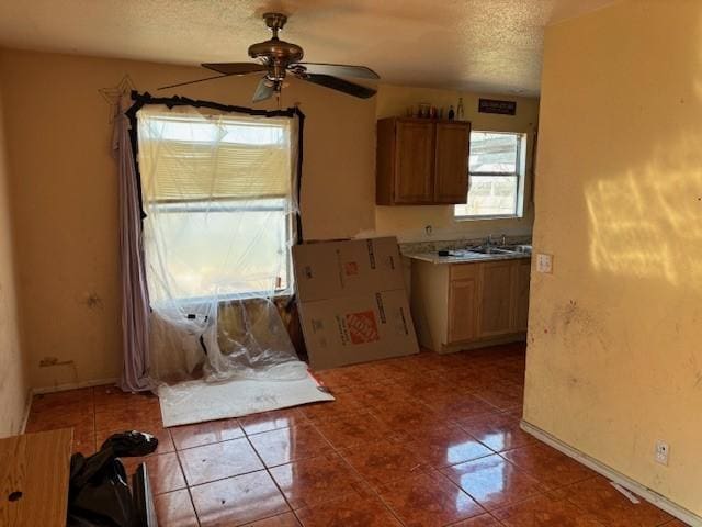 kitchen with ceiling fan, tile patterned floors, sink, and a textured ceiling