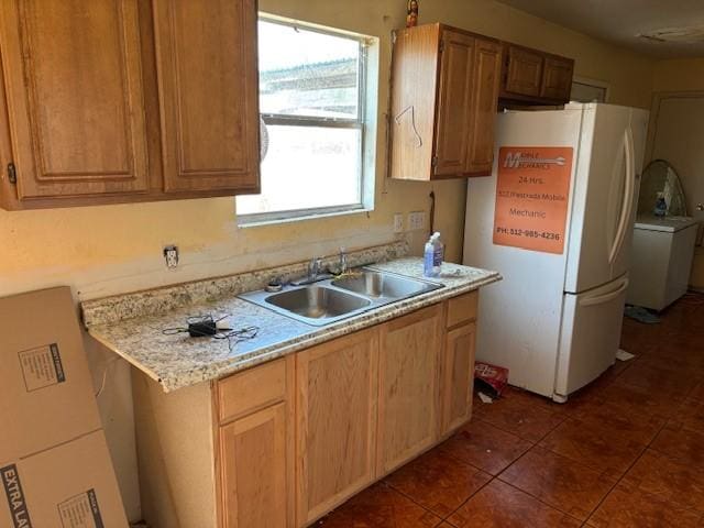 kitchen with white refrigerator, light stone countertops, sink, and dark tile patterned floors