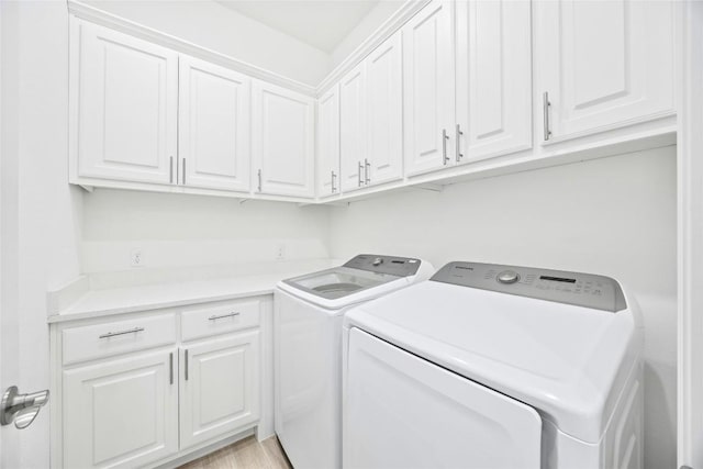 washroom featuring cabinets and washer and clothes dryer