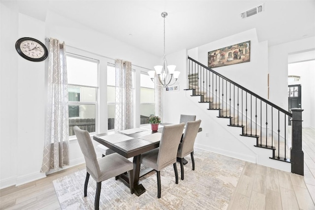 dining space with an inviting chandelier and light hardwood / wood-style flooring