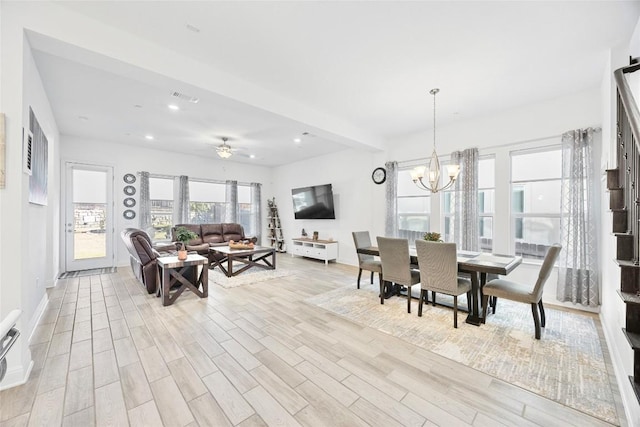 dining area with ceiling fan with notable chandelier and light hardwood / wood-style flooring