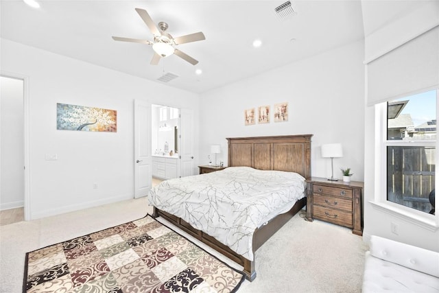 bedroom with ceiling fan, ensuite bath, and light carpet