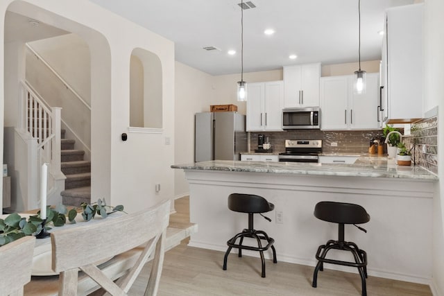 kitchen with pendant lighting, stainless steel appliances, kitchen peninsula, and sink