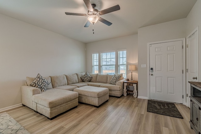 living area with light wood-style floors, ceiling fan, and baseboards