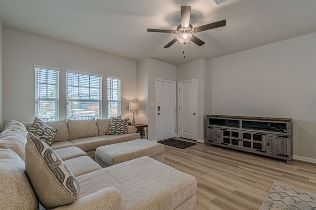 living area featuring a ceiling fan, light wood-style flooring, and baseboards