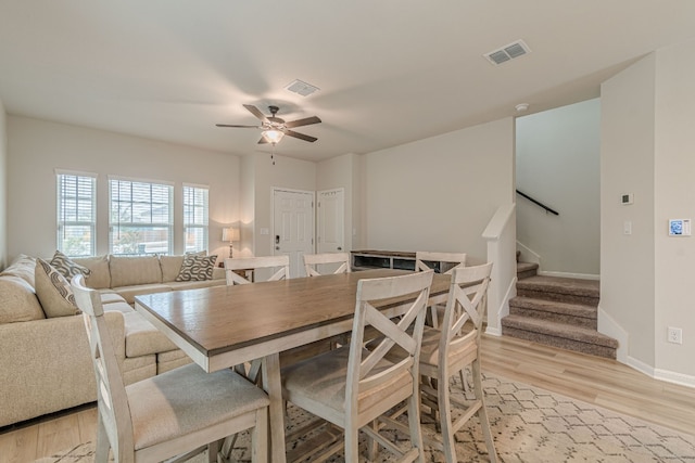 dining area featuring light wood-style flooring, stairway, visible vents, and baseboards