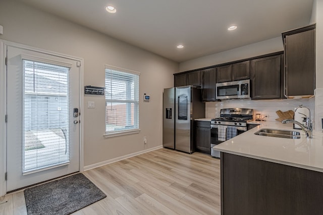 221 Duck Creek Trl, San Marcos, TX 78666 - kitchen featuring appliances with stainless steel finishes, light countertops, dark brown cabinetry, a sink, and light wood-style flooring