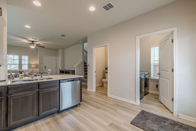 kitchen featuring washing machine and clothes dryer, light countertops, dark brown cabinetry, a sink, and dishwasher