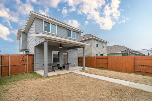 back of house with a lawn, a ceiling fan, a fenced backyard, a gate, and a patio area