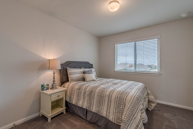 bedroom with dark colored carpet and baseboards