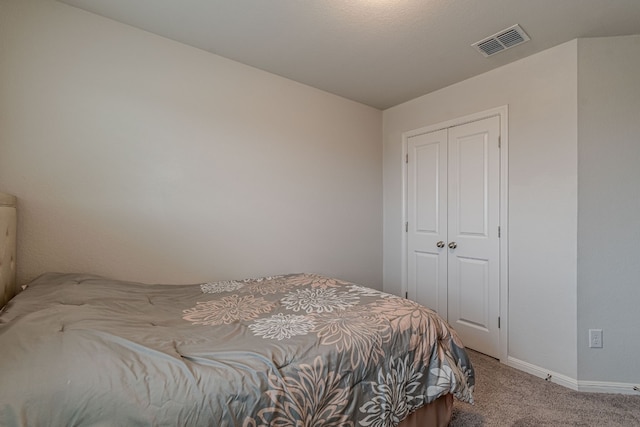 bedroom with a closet, carpet flooring, visible vents, and baseboards