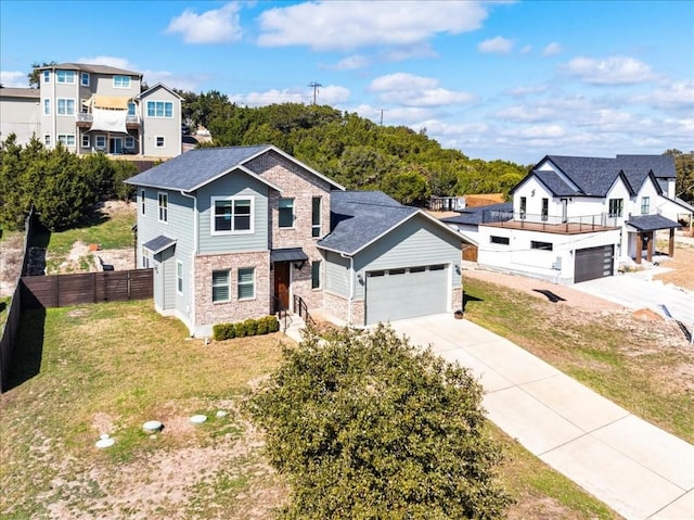 view of front of home featuring an attached garage, a residential view, fence, and concrete driveway