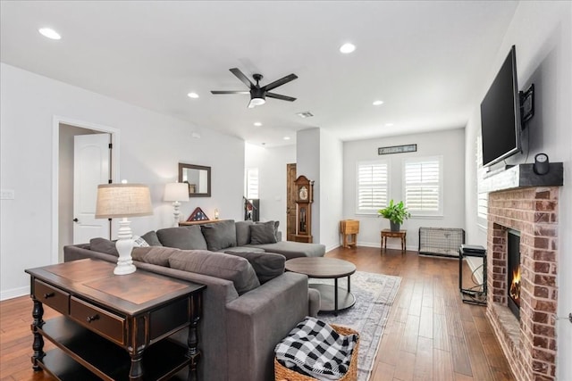 living room featuring ceiling fan, a fireplace, wood finished floors, and recessed lighting