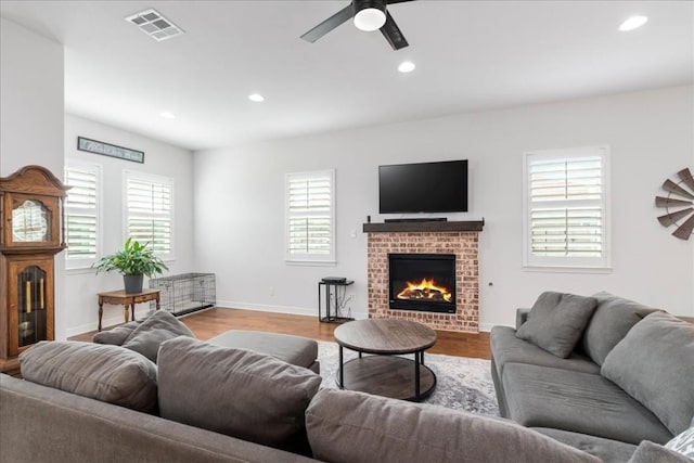 living area featuring recessed lighting, visible vents, a brick fireplace, light wood-type flooring, and baseboards