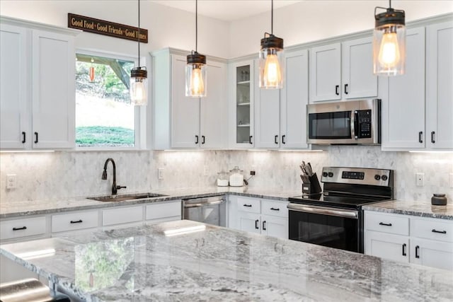 kitchen with hanging light fixtures, glass insert cabinets, stainless steel appliances, and a sink