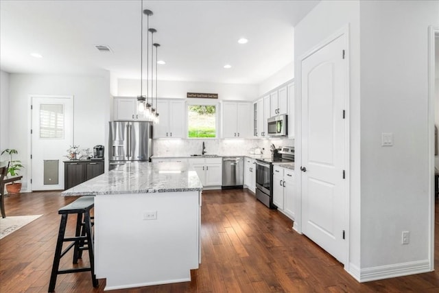 kitchen featuring stainless steel appliances, white cabinets, a kitchen island, and a sink