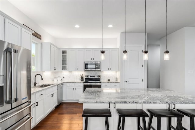 kitchen with stainless steel appliances, pendant lighting, white cabinetry, and a sink