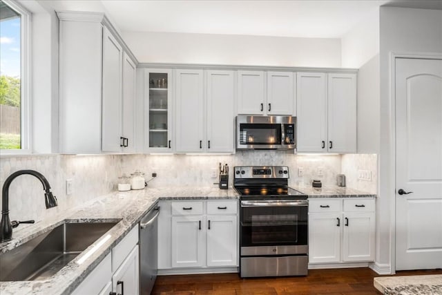 kitchen with white cabinets, glass insert cabinets, stainless steel appliances, and a sink