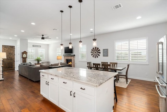 kitchen featuring a center island, visible vents, open floor plan, white cabinetry, and high end refrigerator