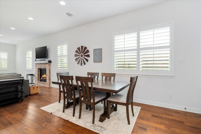 dining area featuring a healthy amount of sunlight, dark wood-style floors, a fireplace, and baseboards