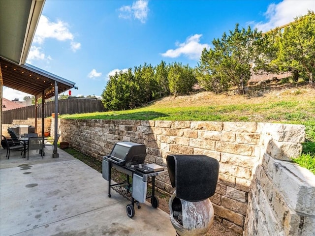 view of patio with outdoor dining space, a fenced backyard, and a grill