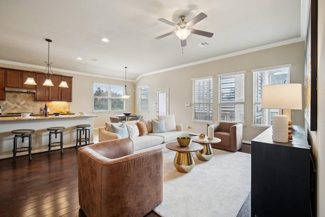 living room featuring crown molding, ceiling fan, recessed lighting, dark wood-type flooring, and visible vents
