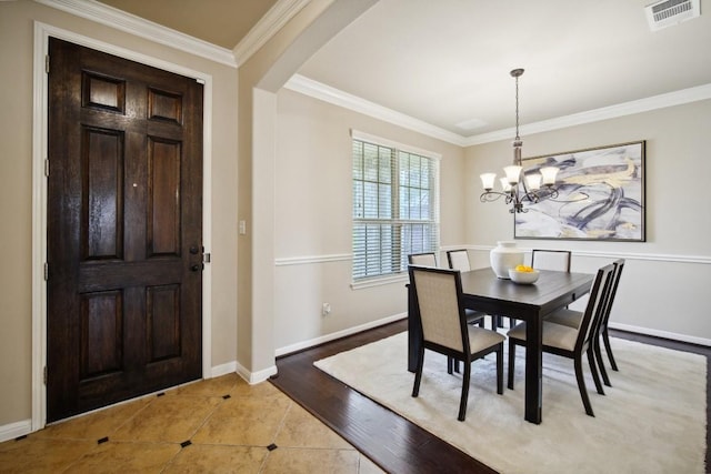 dining space featuring arched walkways, a chandelier, baseboards, visible vents, and ornamental molding