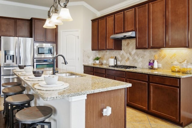 kitchen featuring pendant lighting, sink, crown molding, appliances with stainless steel finishes, and an island with sink