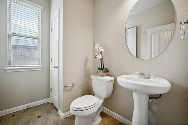 bathroom with a healthy amount of sunlight, baseboards, tile patterned flooring, and toilet