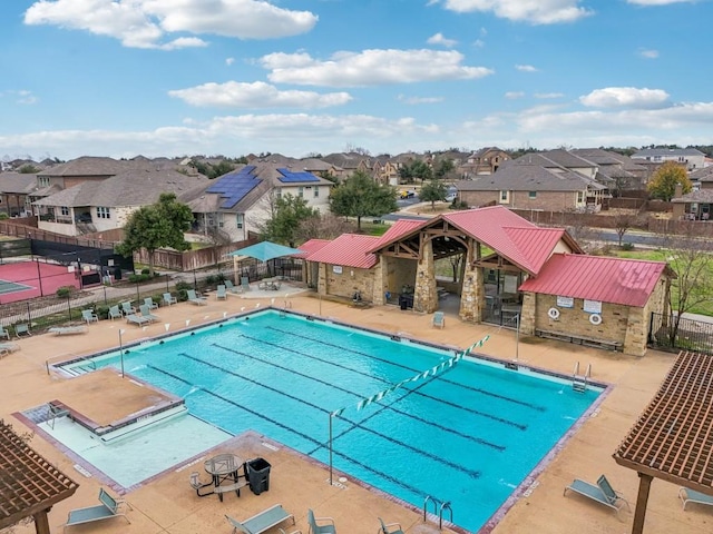 pool with a patio, fence, and a residential view
