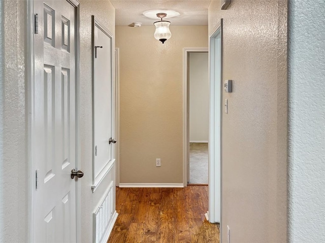 corridor featuring dark hardwood / wood-style flooring and a textured ceiling