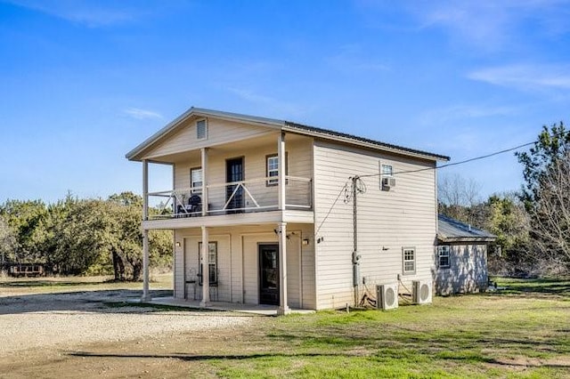 back of property featuring ac unit, a lawn, and a balcony