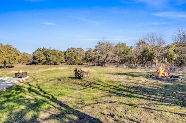 view of yard featuring an outdoor fire pit and a rural view