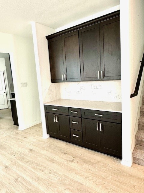 kitchen featuring dark brown cabinetry, a textured ceiling, and light wood-type flooring