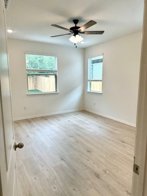 spare room with ceiling fan, plenty of natural light, and light wood-type flooring