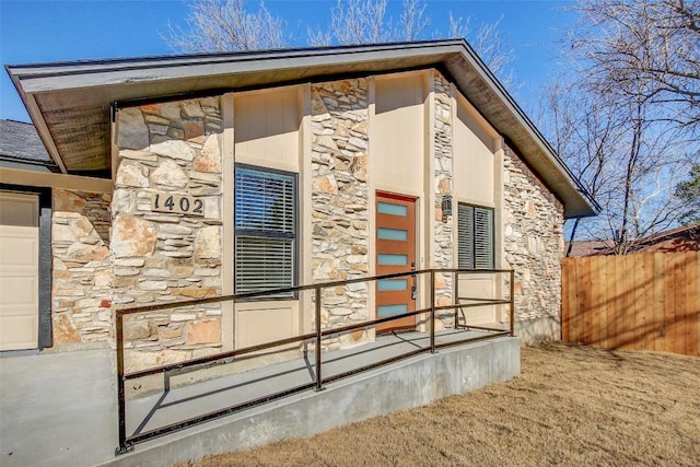 exterior space with fence and stone siding