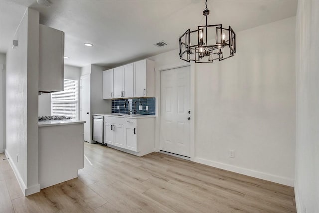 kitchen with dishwasher, white cabinets, backsplash, hanging light fixtures, and light wood-type flooring