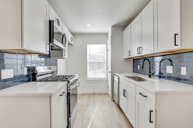 kitchen with a sink, light wood-type flooring, appliances with stainless steel finishes, and light countertops