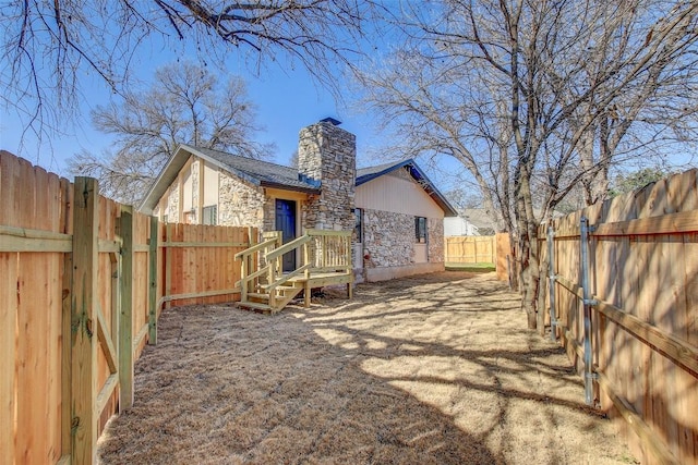 back of property featuring a fenced backyard and a chimney