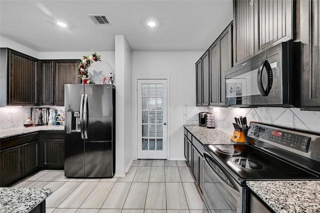 kitchen featuring light stone counters, appliances with stainless steel finishes, dark brown cabinets, and backsplash