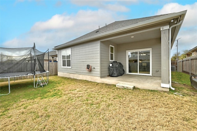 back of house with a patio, a trampoline, and a lawn