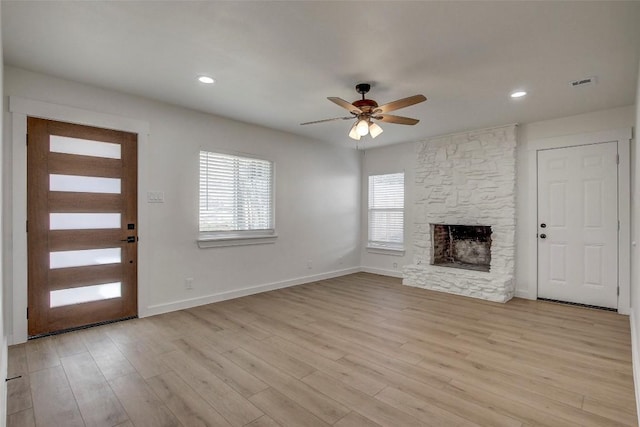 unfurnished living room with visible vents, baseboards, a fireplace, light wood-style floors, and a ceiling fan